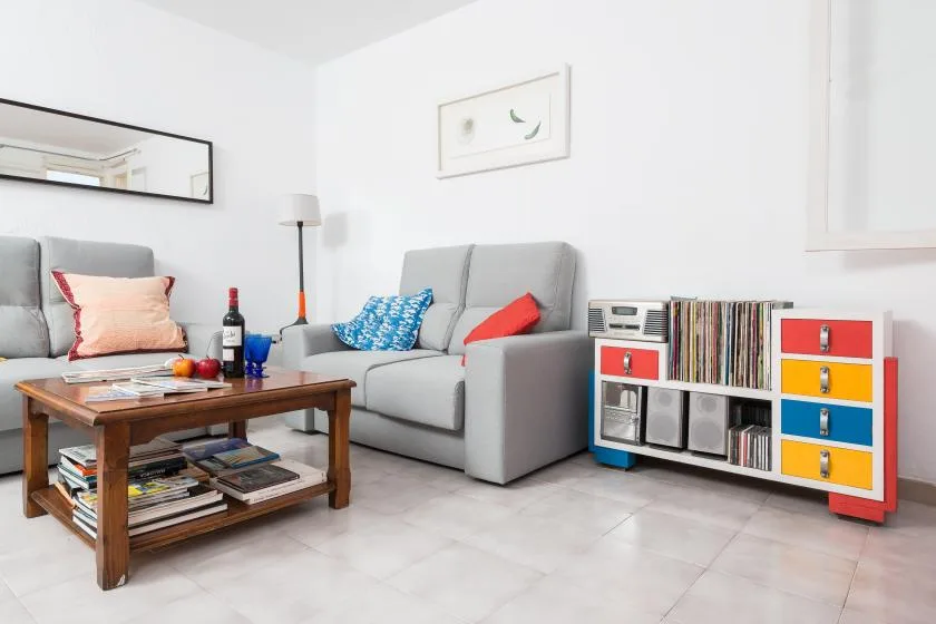 Una sala luminosa con asientos, una mesa de centro y un mueble multimedia colorido.