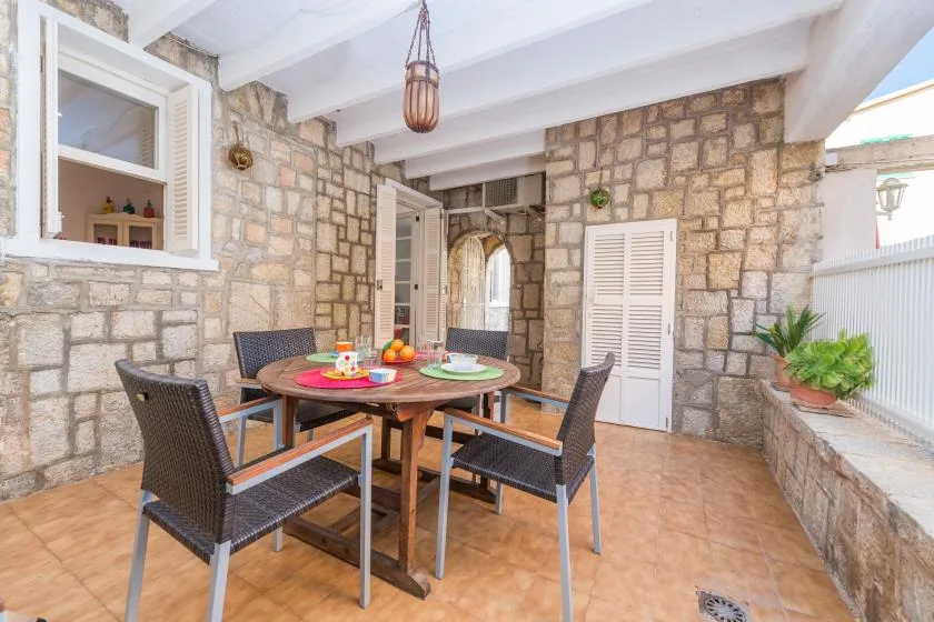 Un comedor con paredes de piedra, mesa de madera y asientos tejidos.