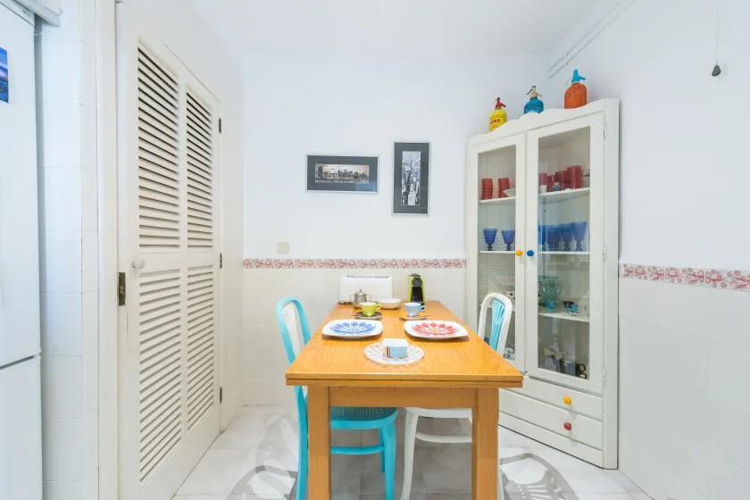 Comedor con una mesa de madera con platos y un armario con puertas de cristal.