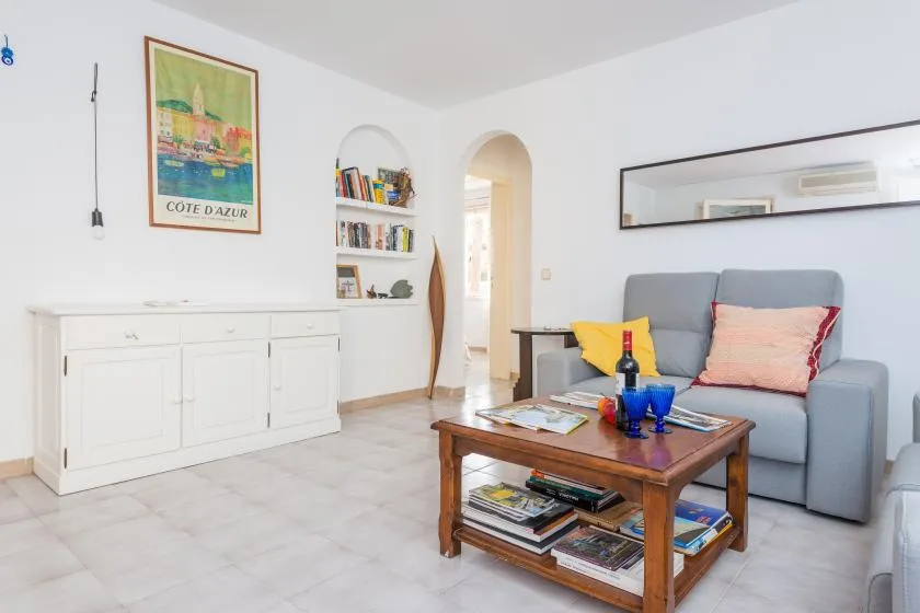 Una sala luminosa con un sofá gris y una mesa de centro de madera.