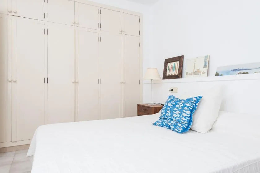 Un dormitorio luminoso con una cama blanca y armarios empotrados.