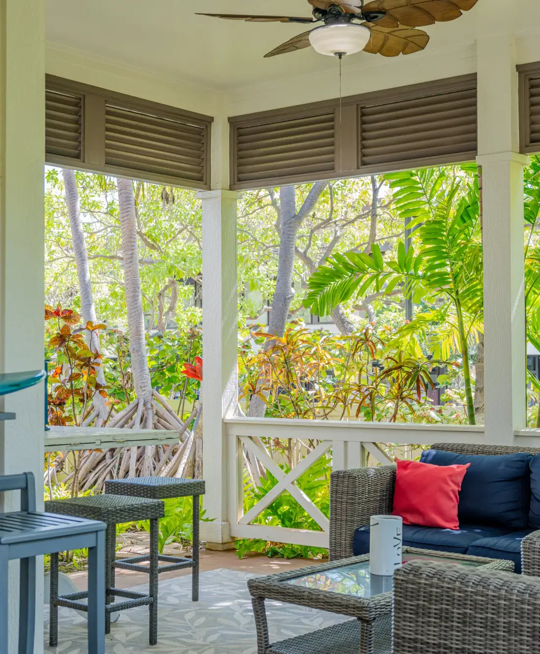 Un patio cubierto con asientos de mimbre da a un jardín frondoso.