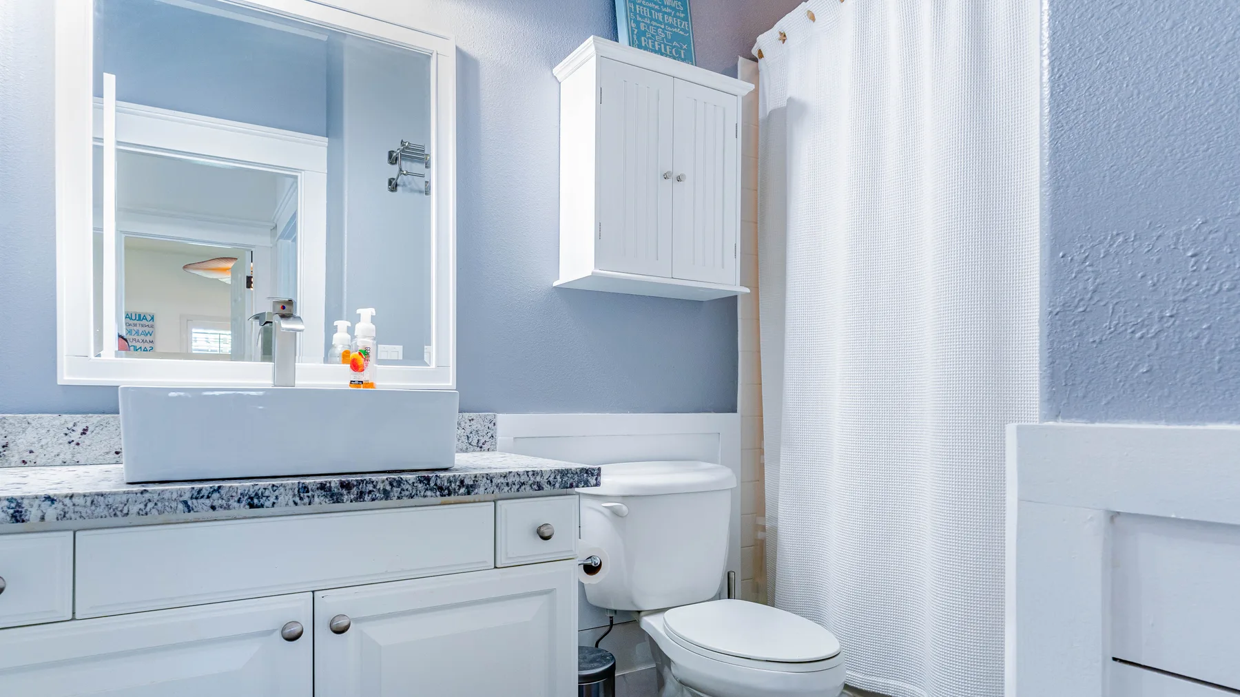 Un baño luminoso con lavabo, inodoro y cortina de ducha blanca.