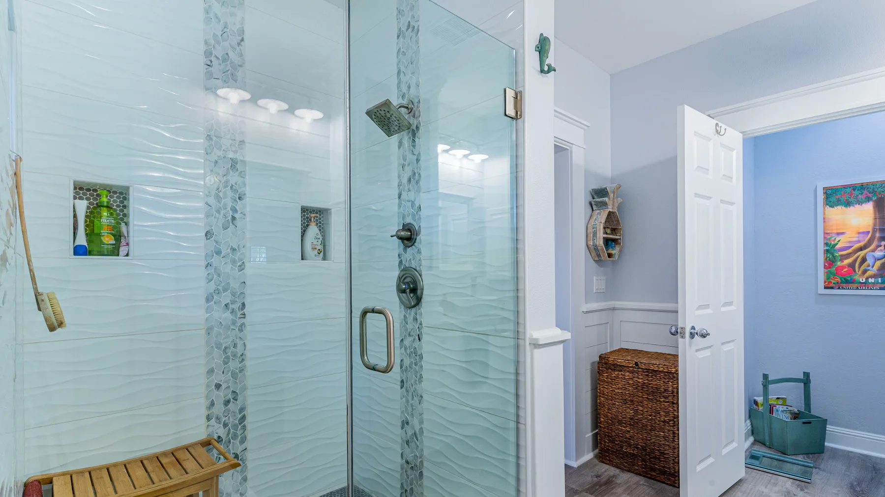 Un baño alicatado con una ducha de vidrio y una cesta tejida para guardar cosas.