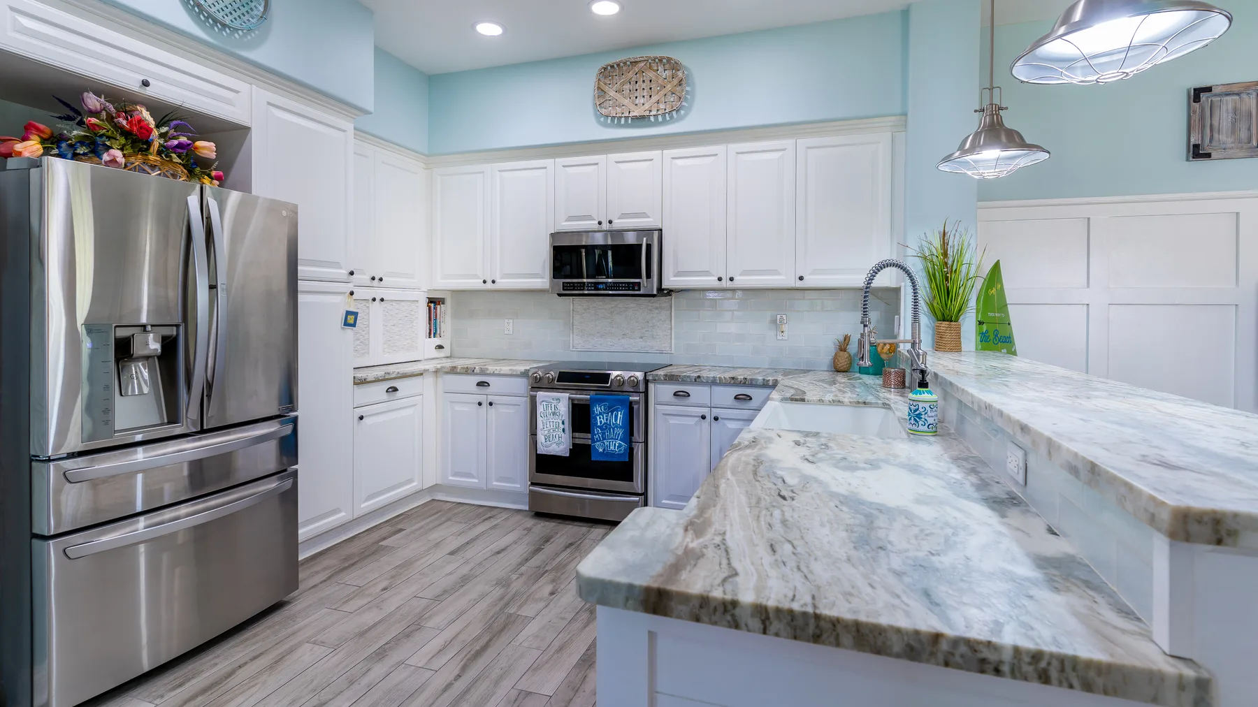 Una cocina luminosa con gabinetes blancos, electrodomésticos de acero inoxidable y una isla grande.