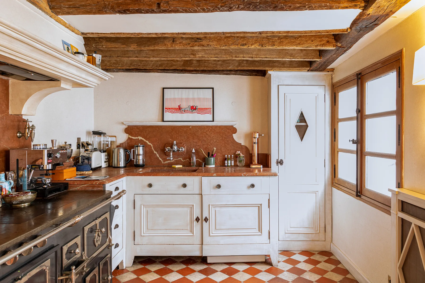 Una cocina con vigas de madera en el techo y suelo de baldosas.