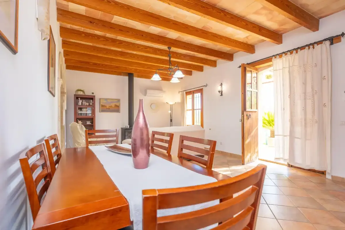 Comedor con una mesa larga de madera bajo vigas de techo expuestas.