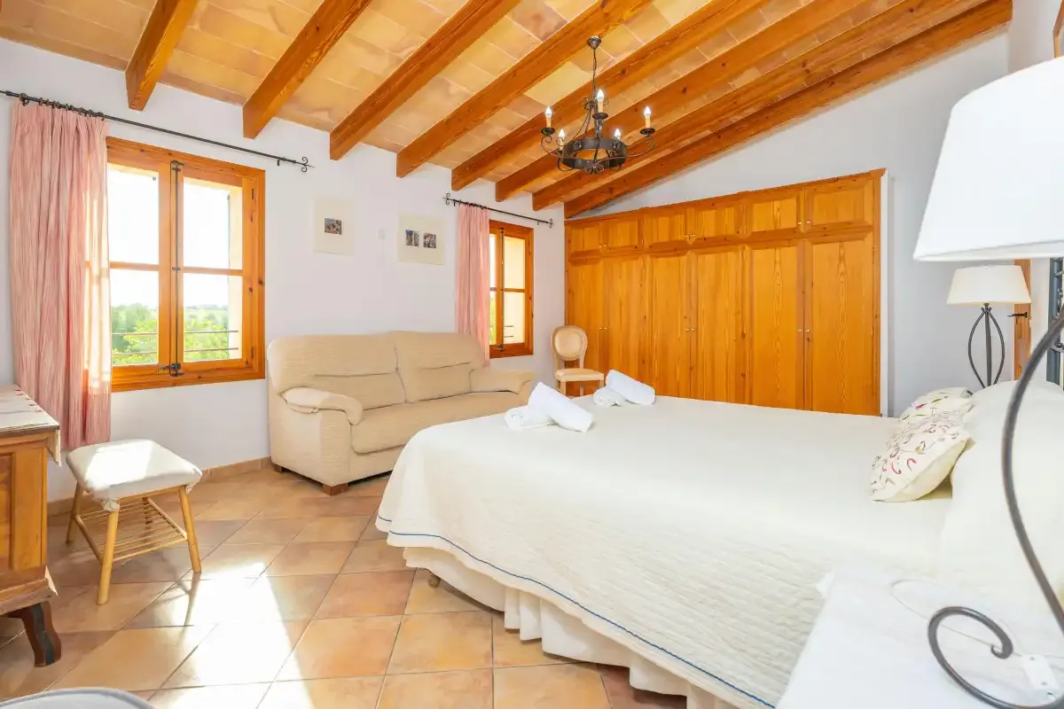Un dormitorio con una cama grande, asientos y vigas de madera en el techo.