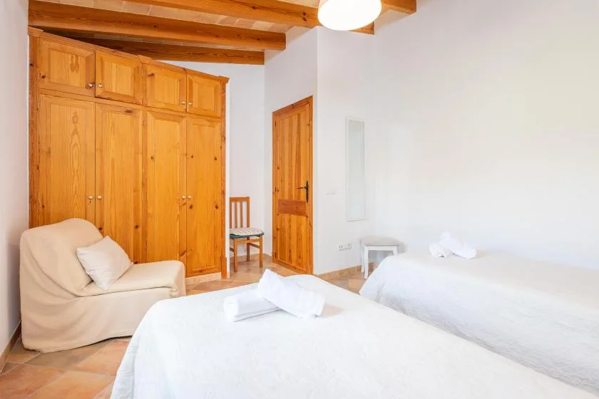 Un dormitorio con camas, un asiento acolchado y armarios de madera.