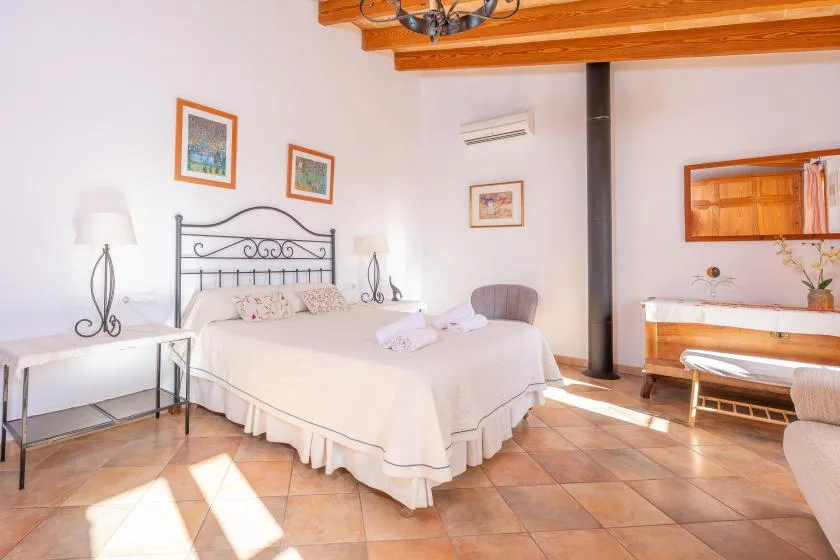 Un dormitorio luminoso con una cama grande, cuadros enmarcados y vigas expuestas.
