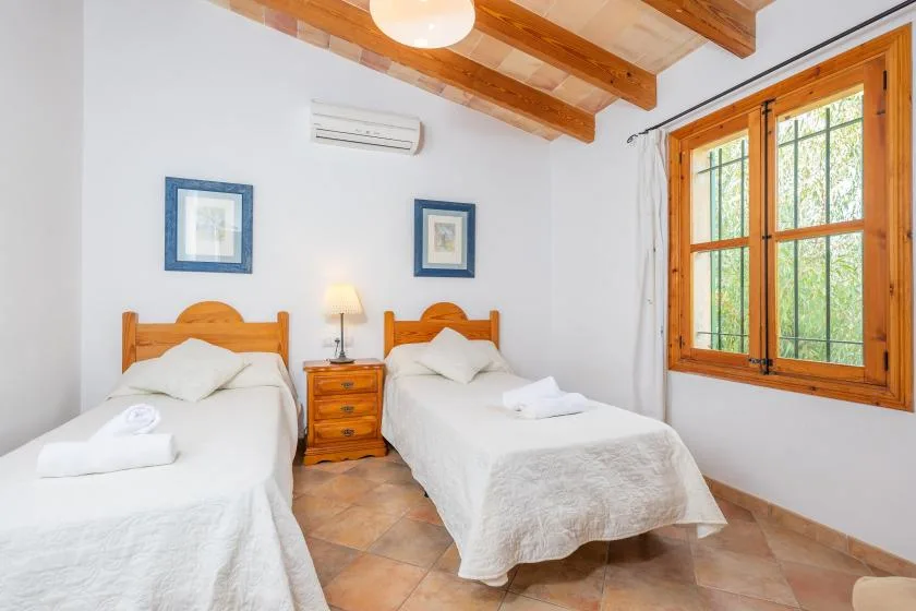 Un dormitorio con dos camas, una mesita de noche y una gran ventana con marco de madera.