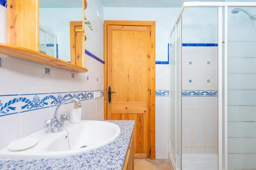 Un baño con lavabo, puerta de madera y ducha de vidrio.
