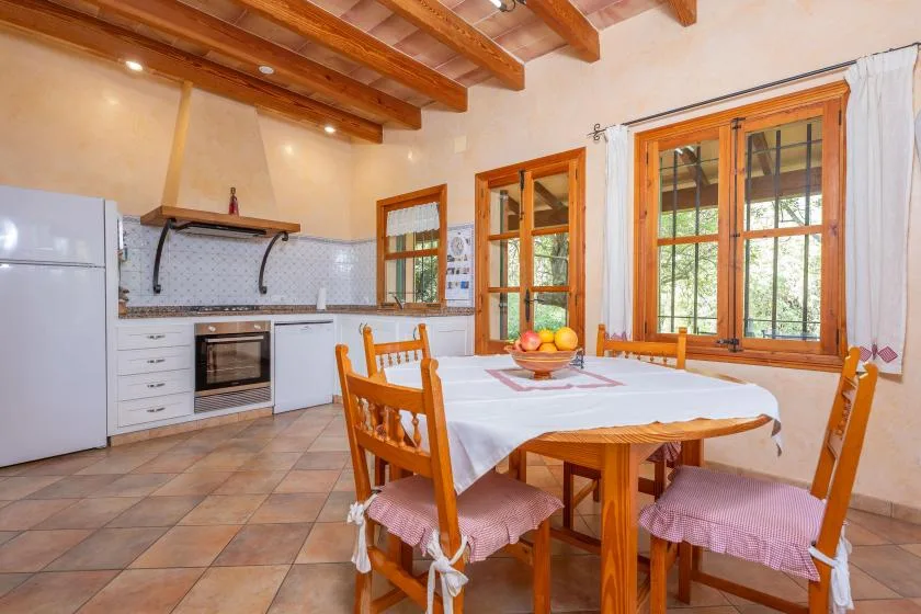 Una cocina y comedor con una mesa junto a grandes ventanas.