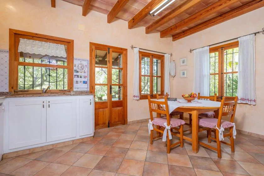 Un comedor luminoso con una mesa de madera junto a varias ventanas.