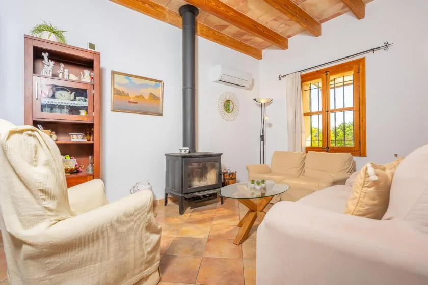 Una sala luminosa con asientos, una estufa de leña y vigas de techo expuestas.
