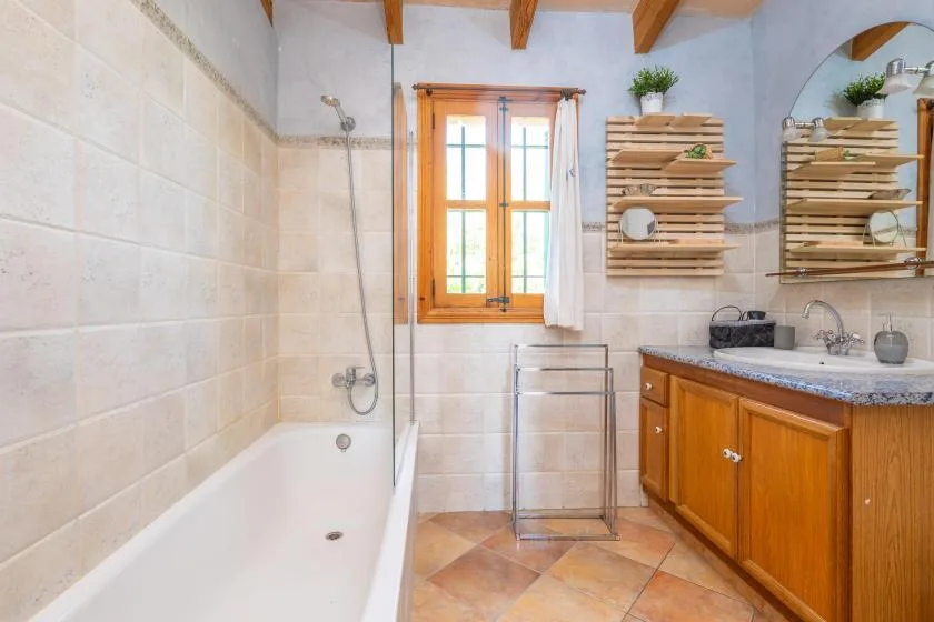 Un baño con azulejos, bañera, mueble de madera y ventana.