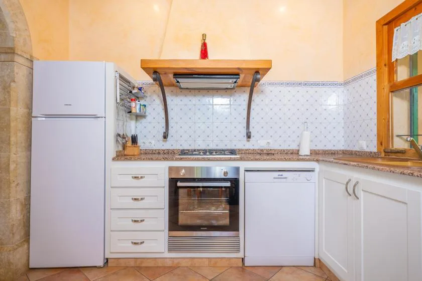 Una cocina luminosa con refrigerador, horno y encimera de madera.