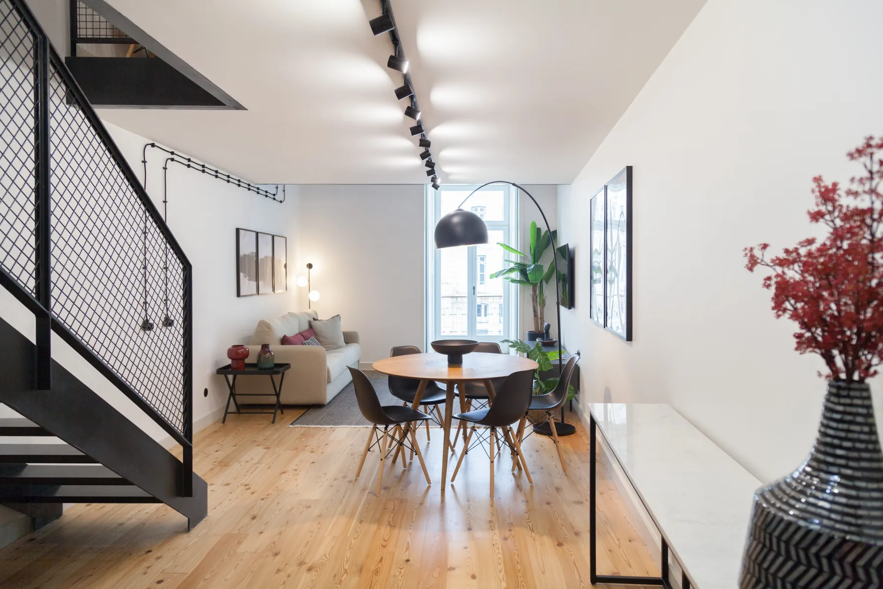 Una luminosa sala de estar y comedor diáfana, con una mesa junto a una escalera.