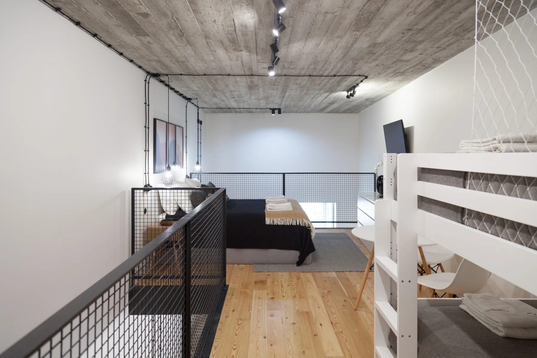 Zona de descanso tipo loft con una cama y una litera blanca.