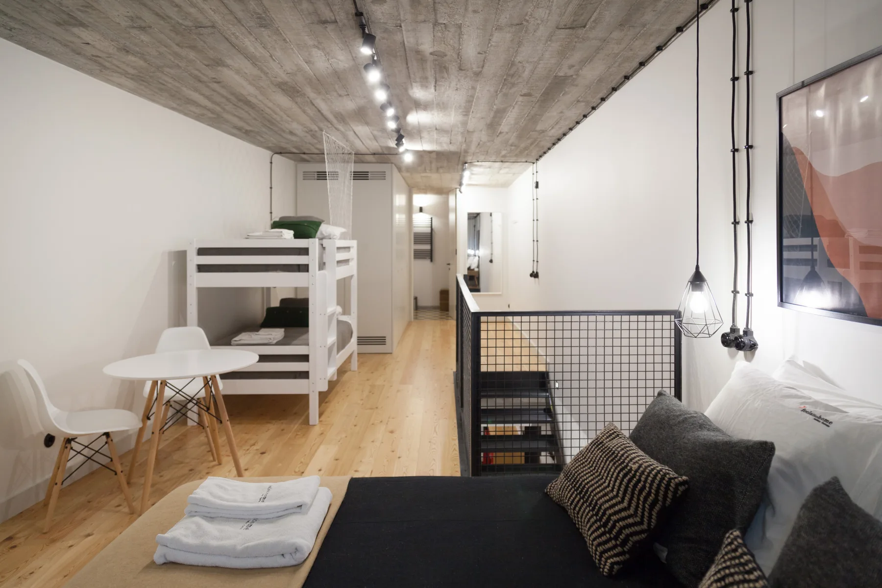 Una habitación tipo loft con literas, una zona de estar y suelo de madera.