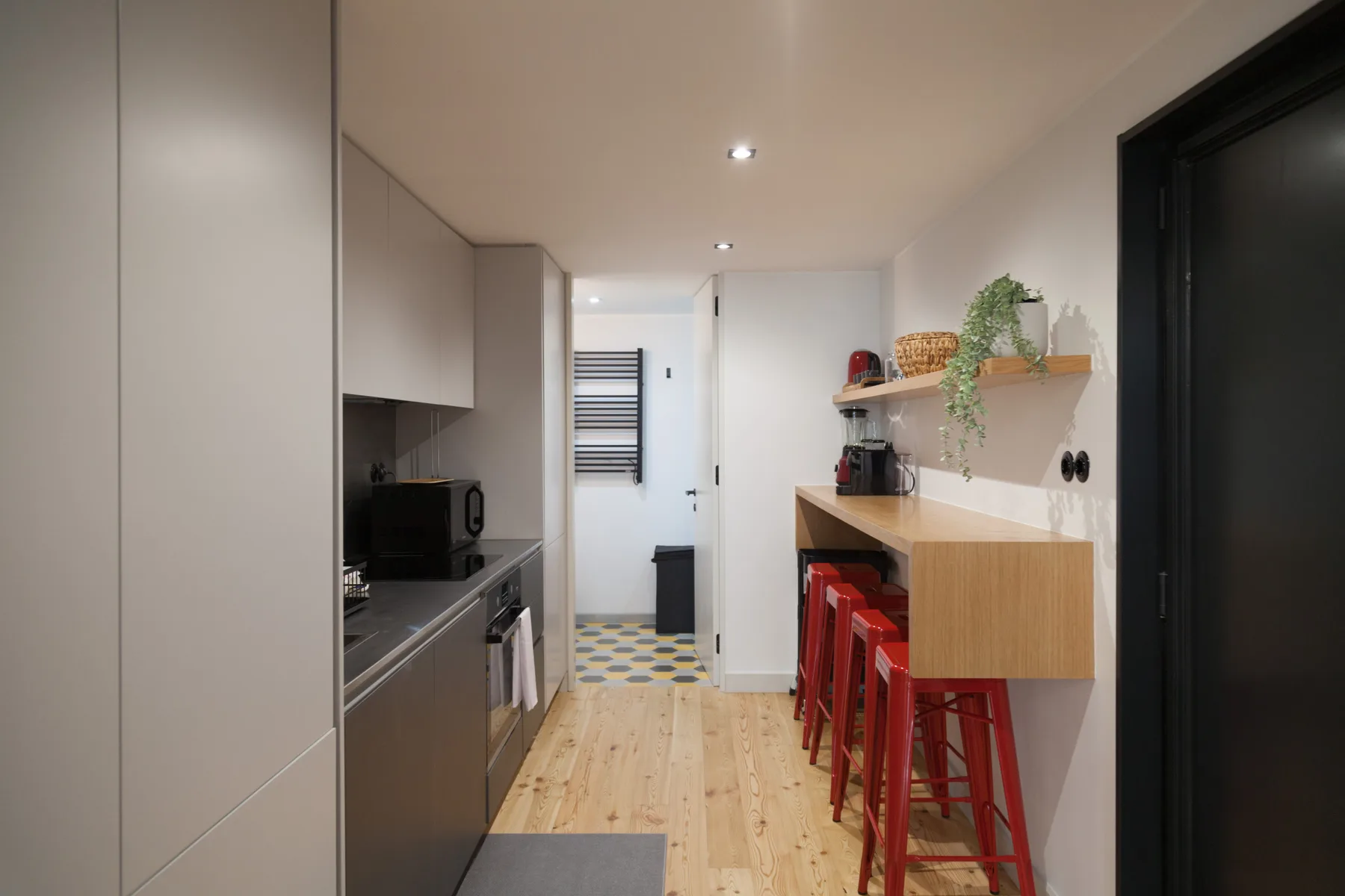 Una cocina estrecha con una barra y taburetes rojos junto a la pared.