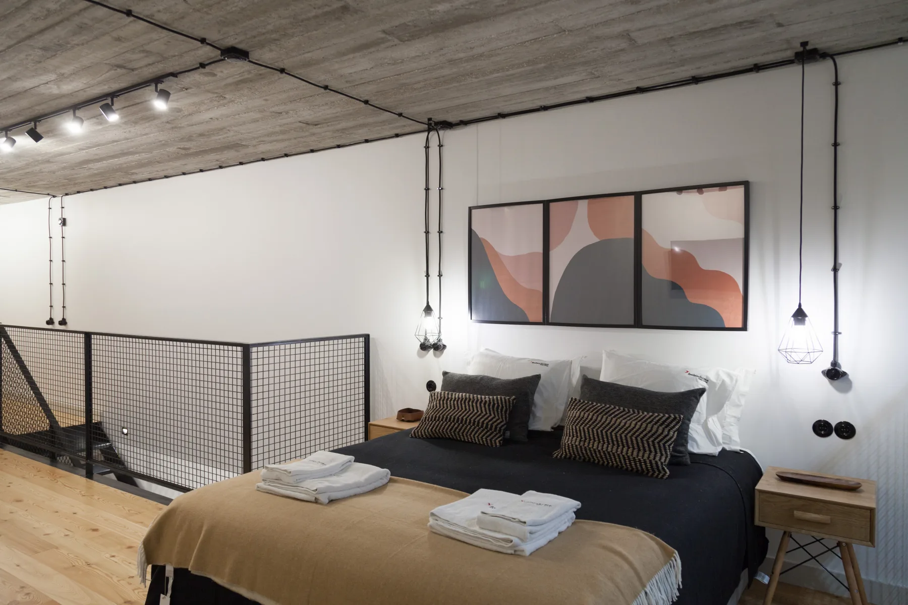 Un dormitorio con una cama, toallas dobladas y arte abstracto encima.