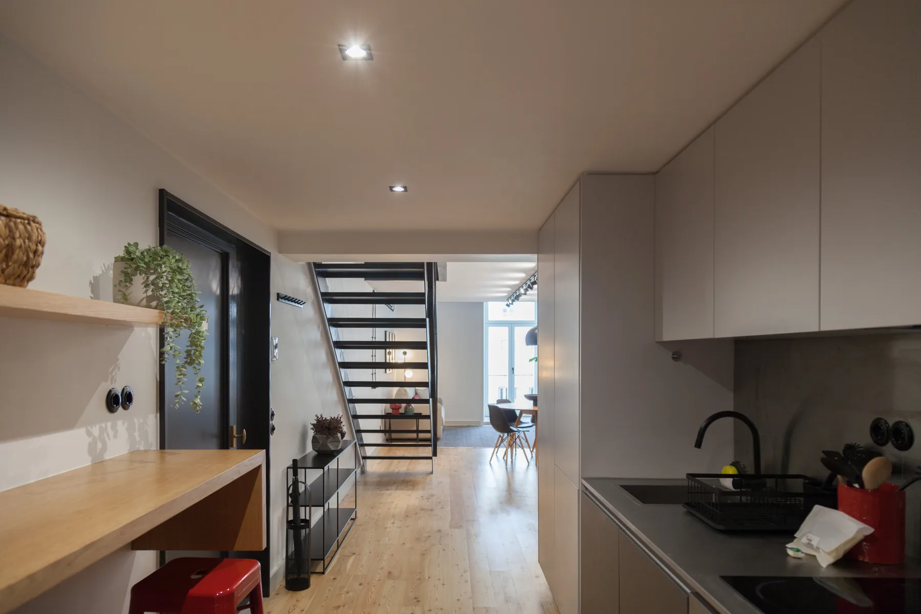Una cocina moderna se abre a un comedor, con una escalera entre ambos.