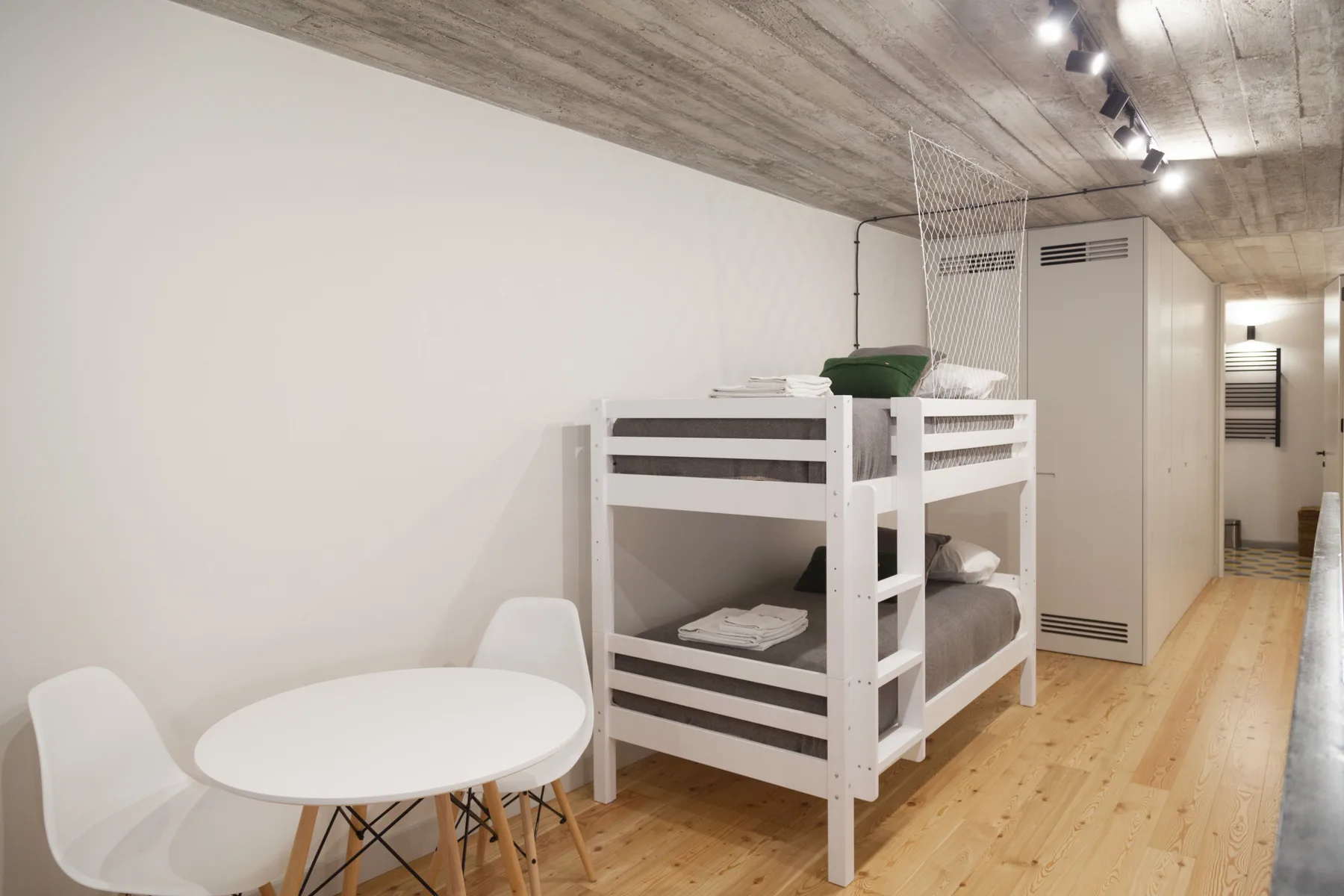 Un dormitorio con literas y una pequeña mesa redonda al lado.