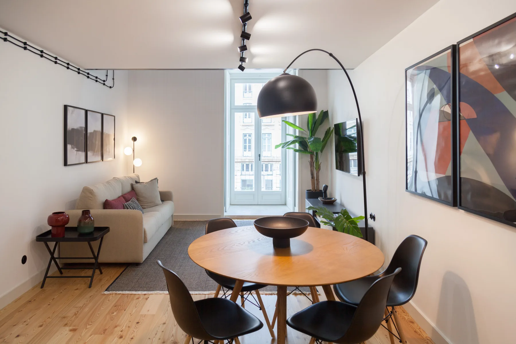 Una luminosa sala de estar y comedor con sofá, mesa redonda y una ventana amplia.