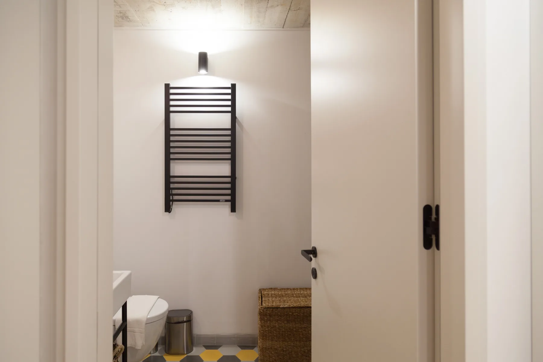 Un baño con un toallero calefactable en la pared y un inodoro.
