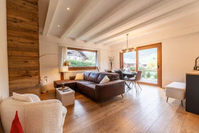 A bright living room with seating arranged around a coffee table and large windows.