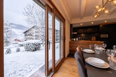 A dining area beside large windows overlooks a snowy outdoor scene.