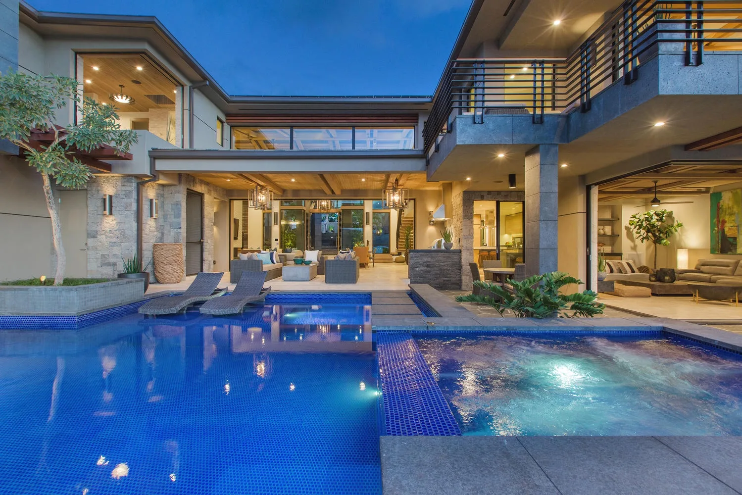 An outdoor pool beside a modern multi-story building, with seating along the water.