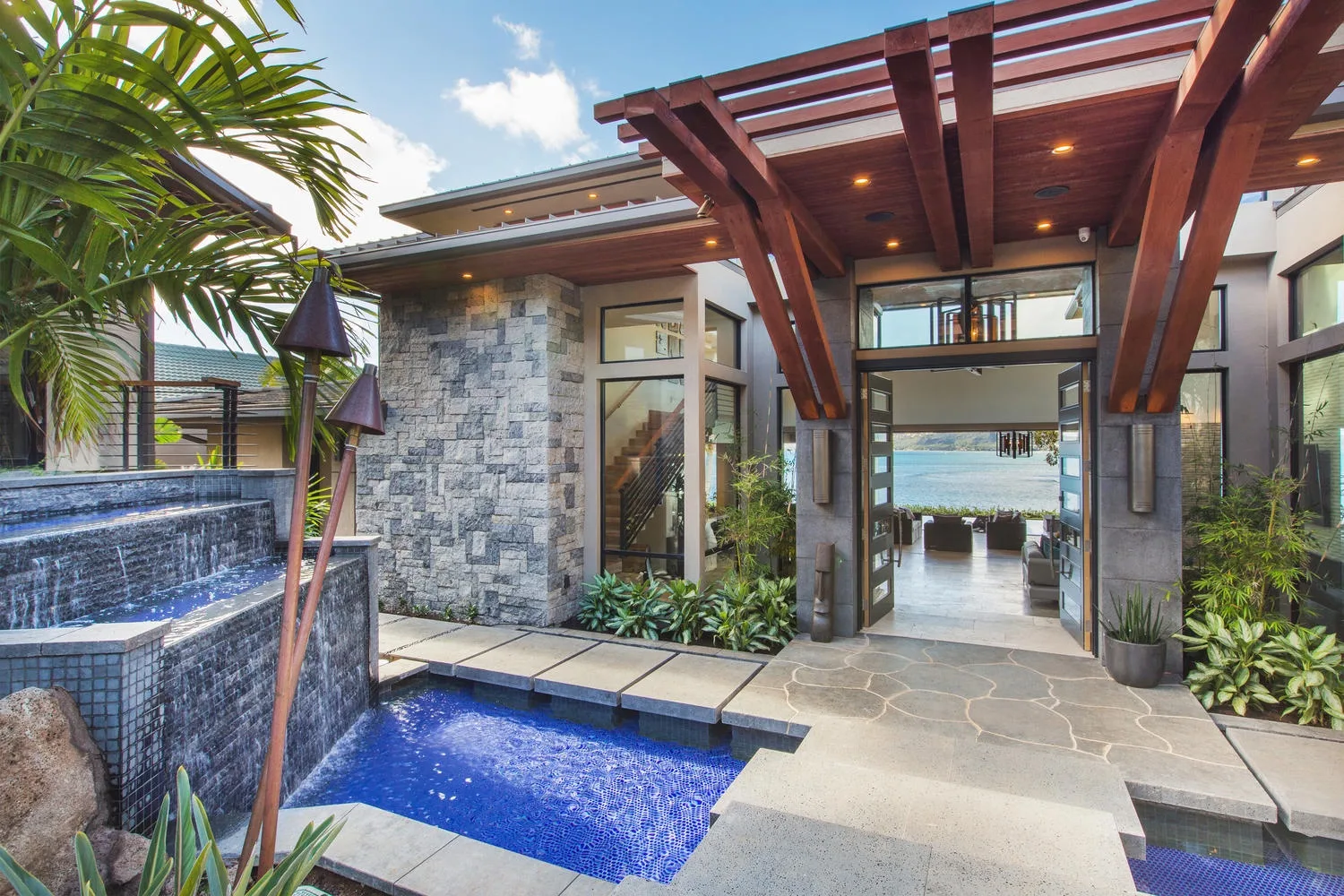 A poolside patio with a stone walkway and a covered entrance.