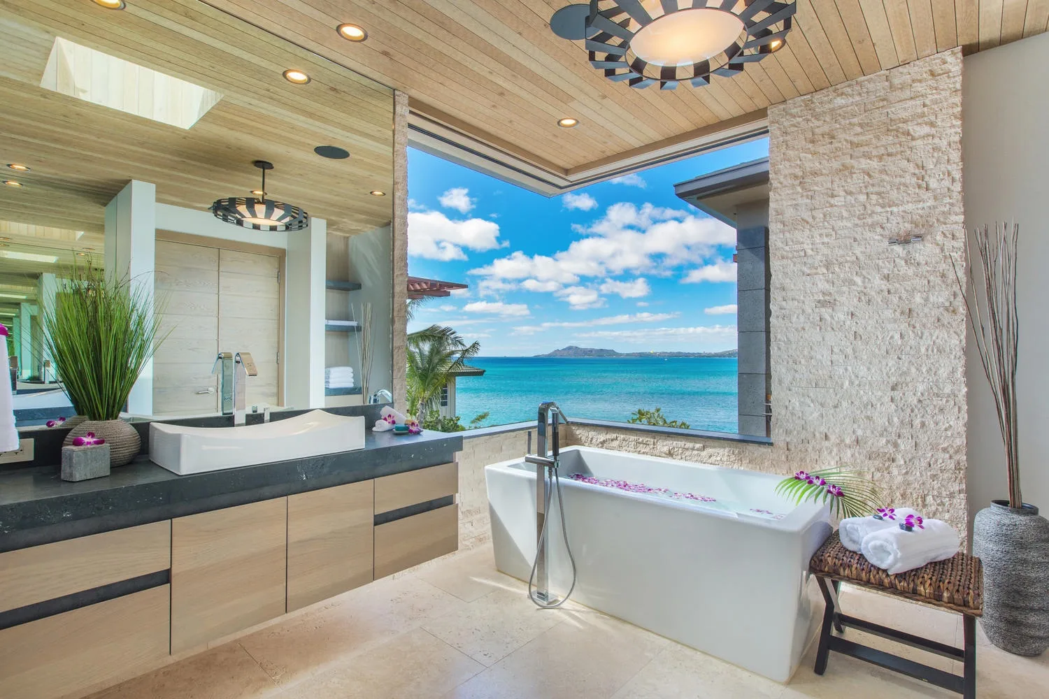 A bathroom with a freestanding bathtub beside a large window overlooking the sea.
