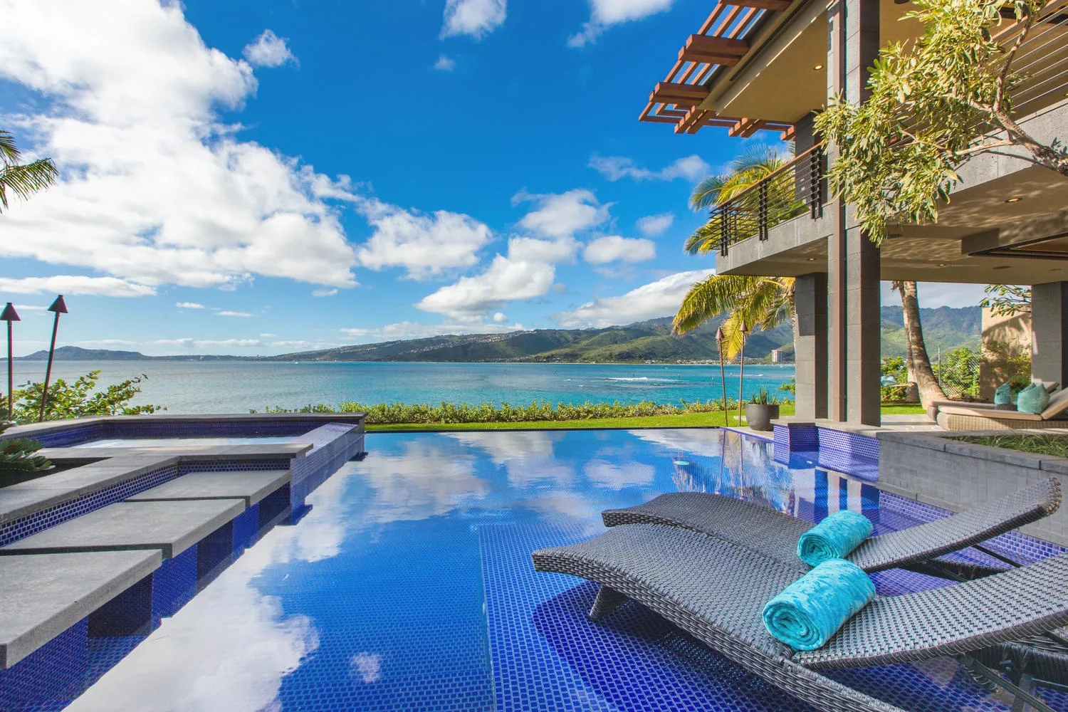An infinity pool overlooks the sea beside a modern building.