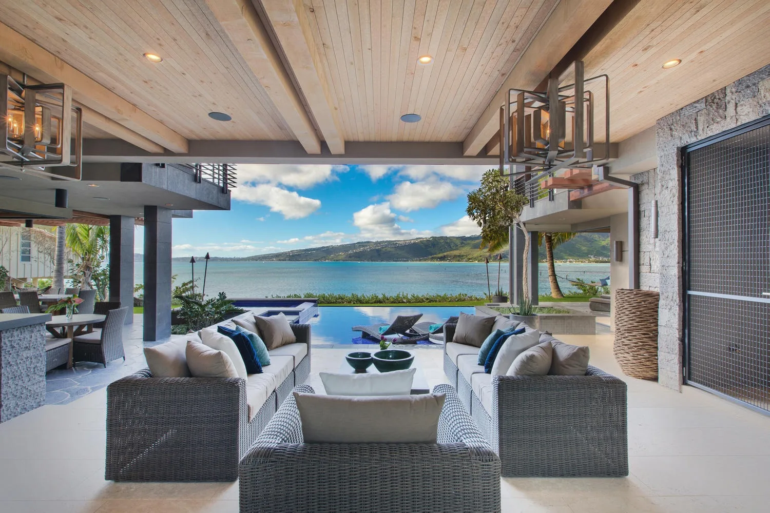 An open-air lounge with seating overlooks a pool and a lake.