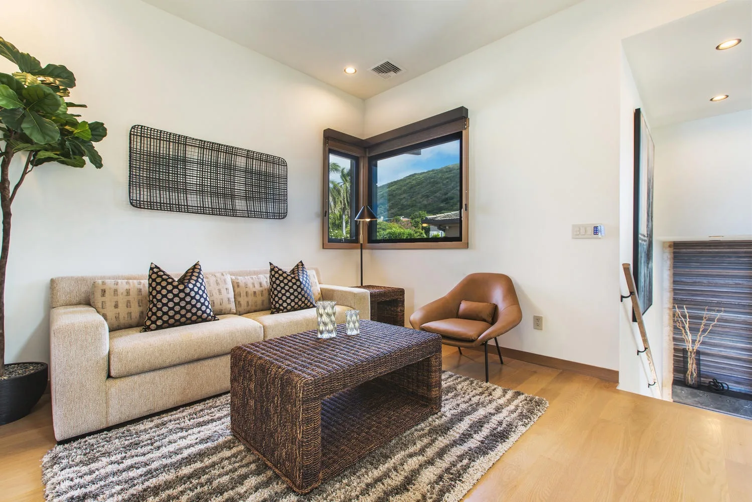 A living room with a sofa, coffee table, and windows overlooking a green hillside.