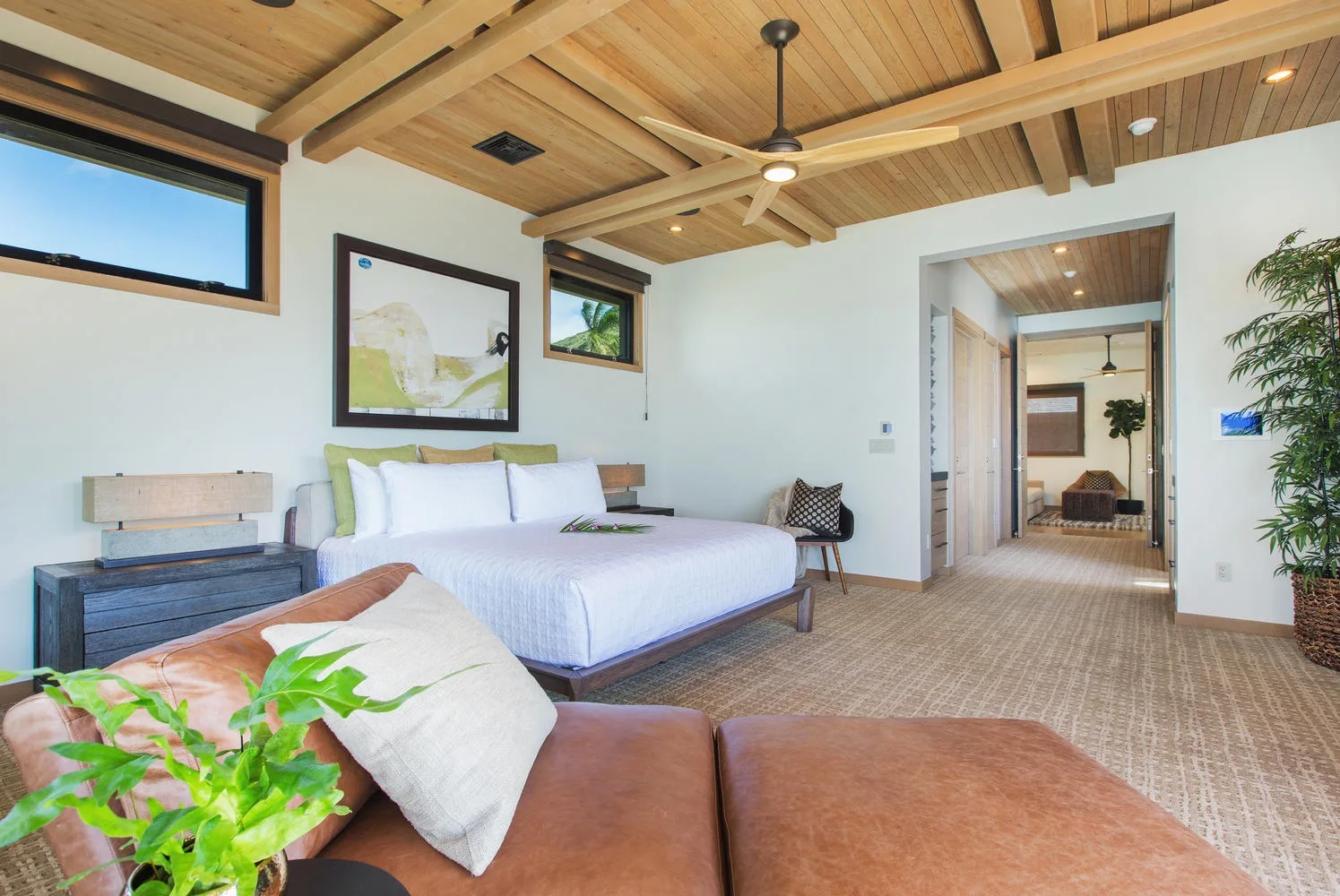 A bedroom with a bed, a seating area, and a wood-paneled ceiling.