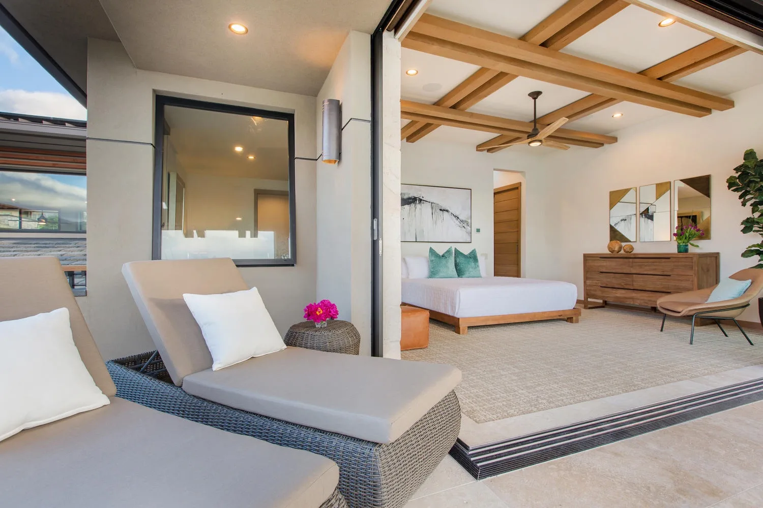 A bedroom opens onto a patio with cushioned seating and a bed.