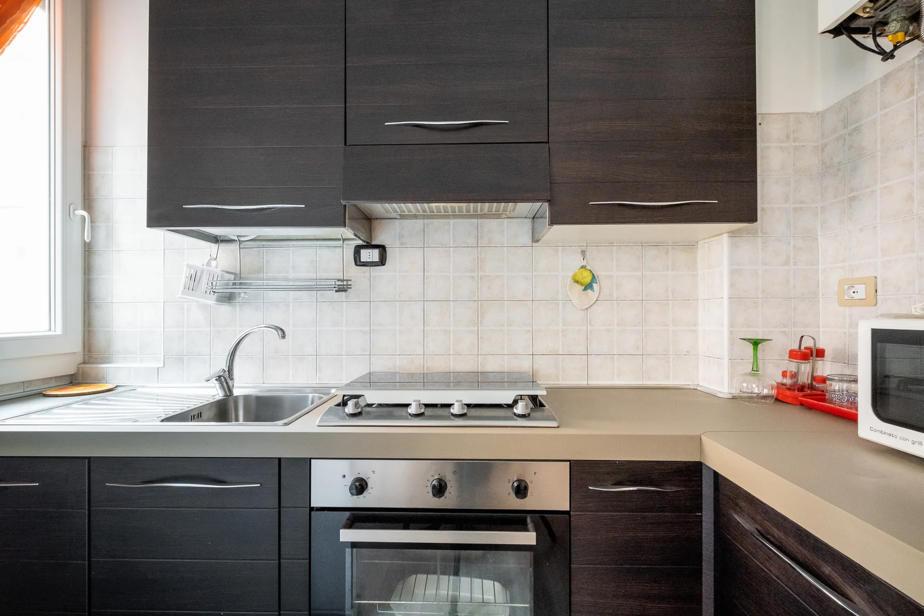 A kitchen with dark cabinets, a cooktop, and an oven.