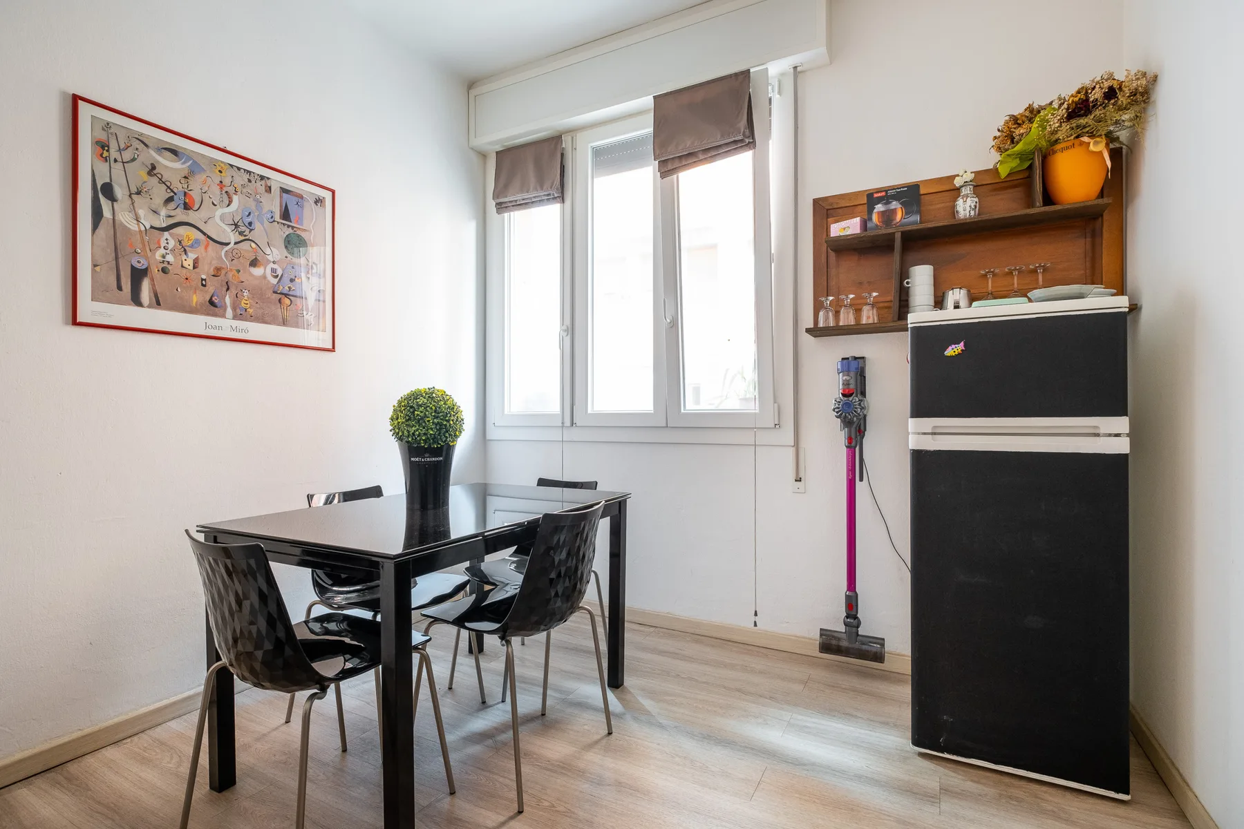 A dining area with a table and chairs beside a bright window.