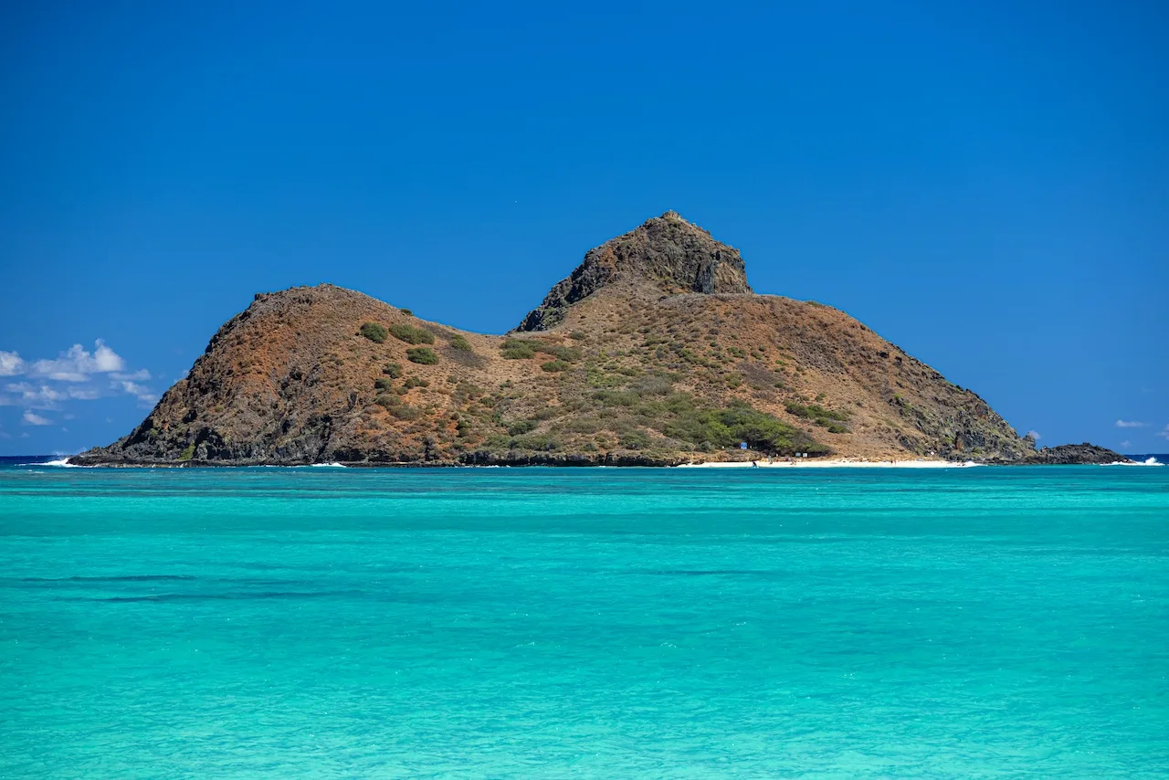 A small rocky island rises behind bright turquoise water.
