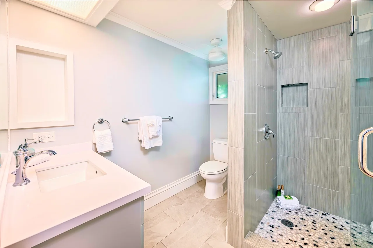 A bathroom with a sink, toilet, and tiled shower area.