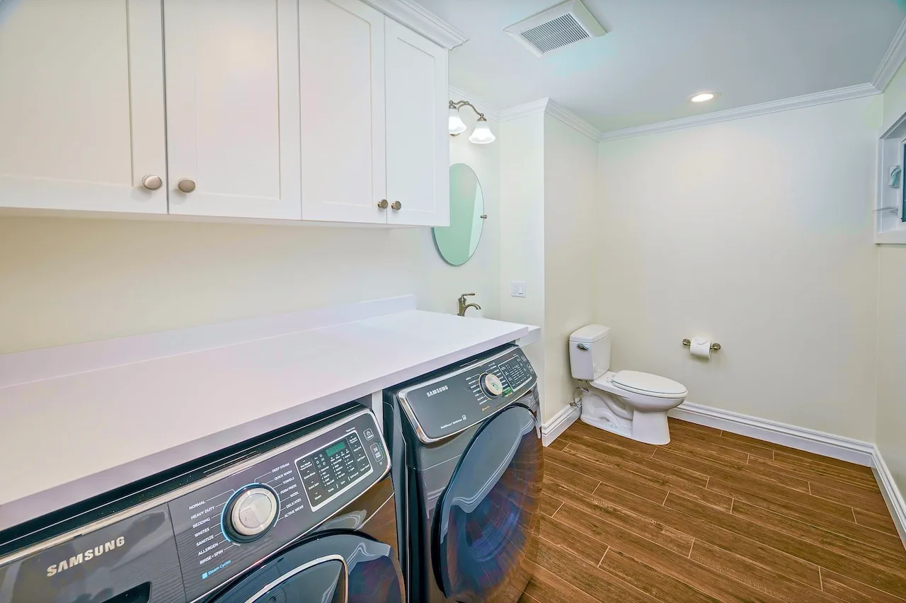 A laundry area with front-loading machines beside a toilet.