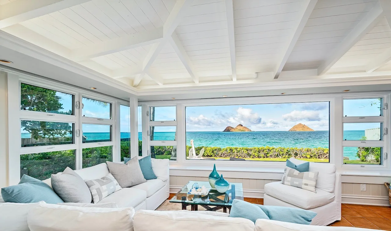 A bright living room with seating facing wide windows and an ocean view.