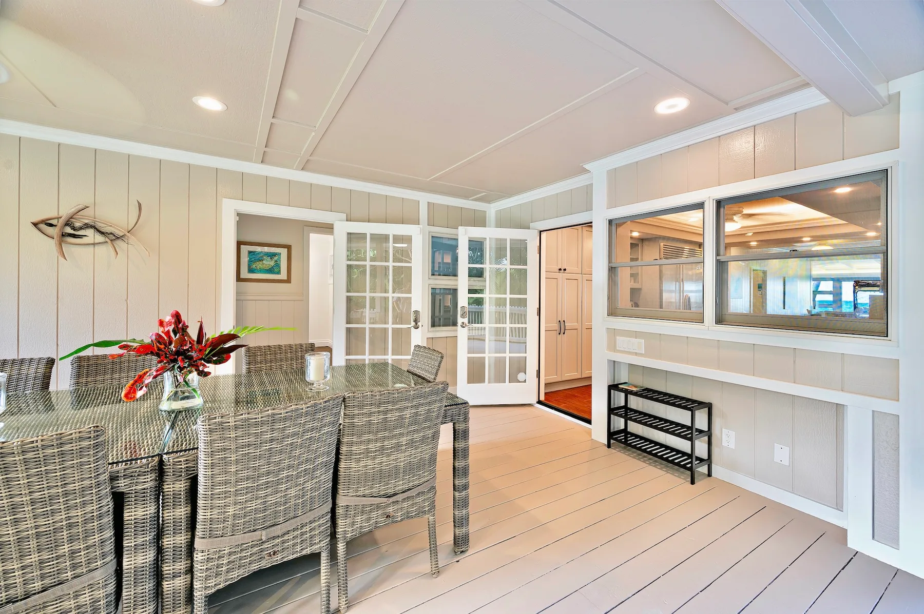 A dining area with woven seating and glass-paneled doors.