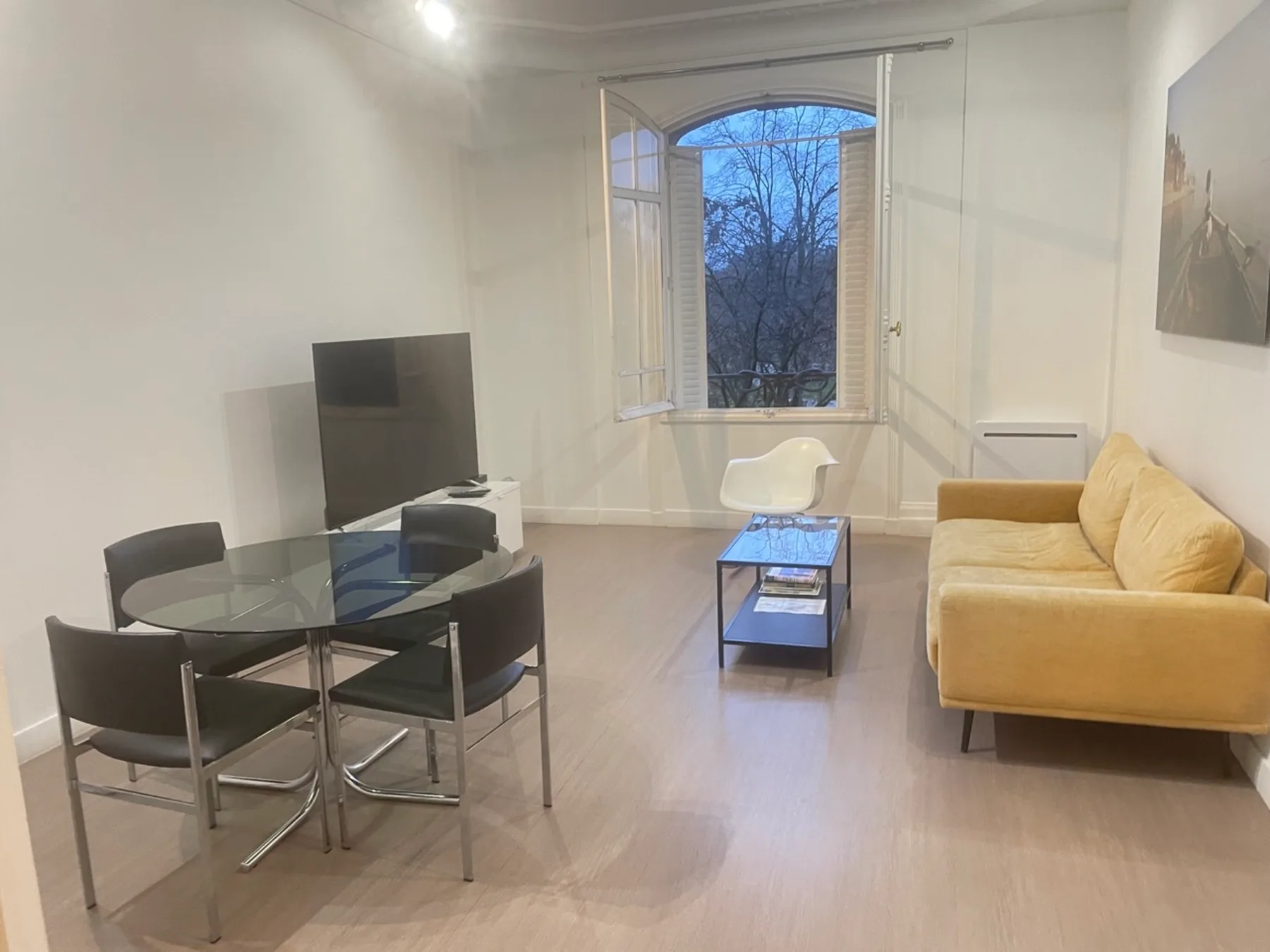 Una sala luminosa con asientos, una mesa de comedor de vidrio y una ventana amplia.