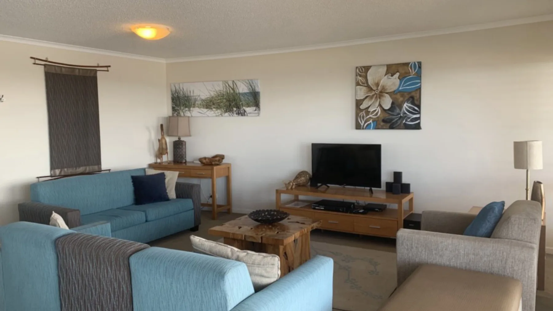 Una sala de estar con asientos alrededor de una mesa de centro y un televisor.