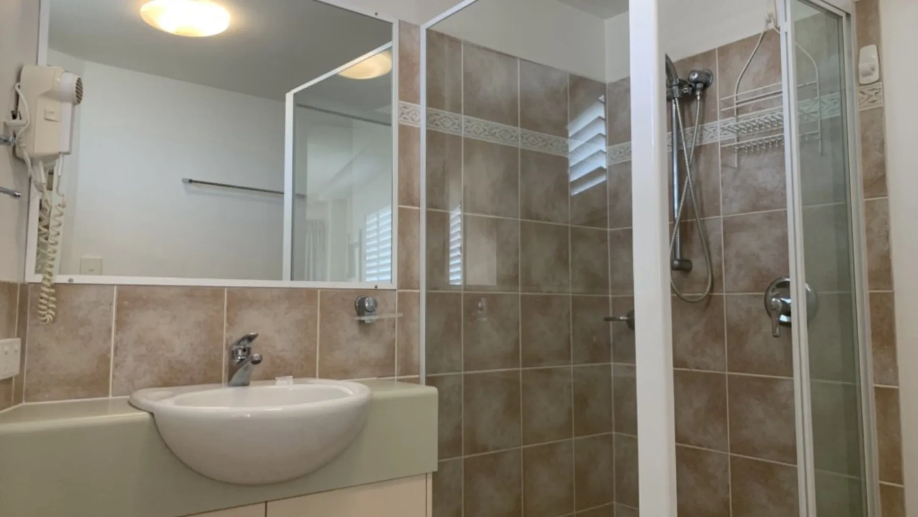 Baño con lavabo y ducha con paneles de vidrio.